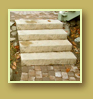 Cobblestone style pavers lead up stone stairs and past a tiny round patio